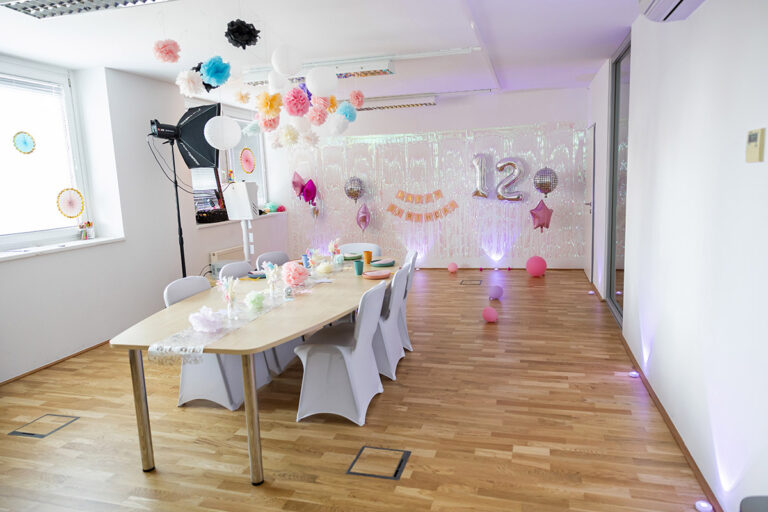 Partyraum mit dekoriertem Tisch und mit Sesseln mit Hussen