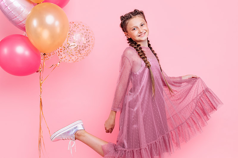Teenager vor einem rosa Hintergrund mit Ballons